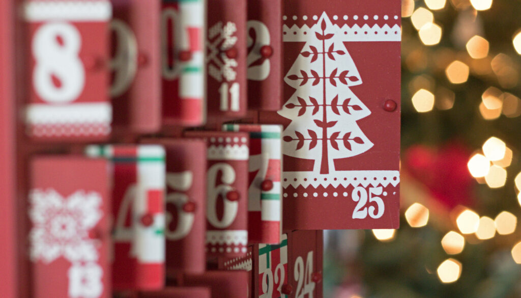 A close-up of a creative papercraft advent calendar with numbered rolls featuring festive Christmas designs.