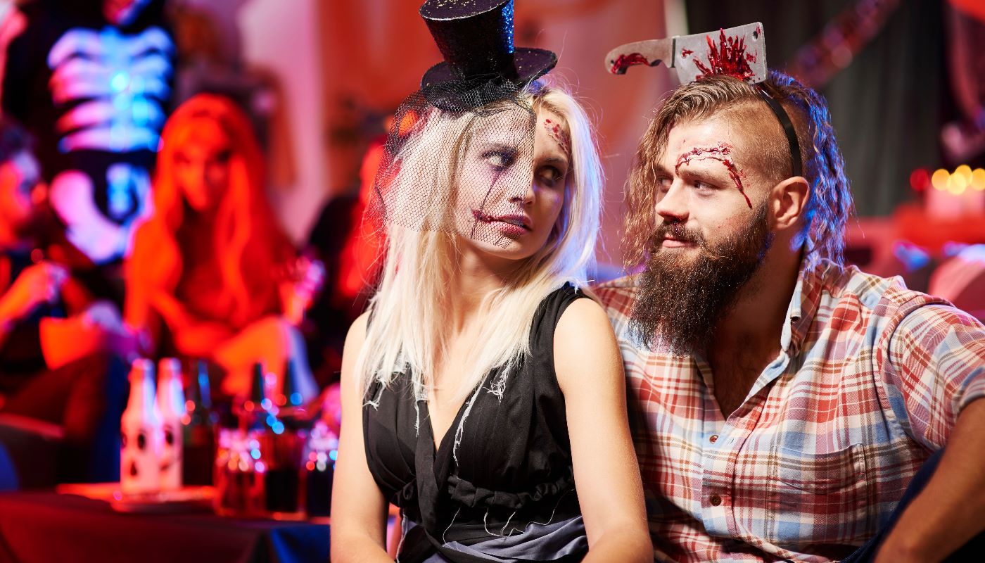 A couple dressed up for Halloween, one as a zombie bride, at a spooky-themed party.