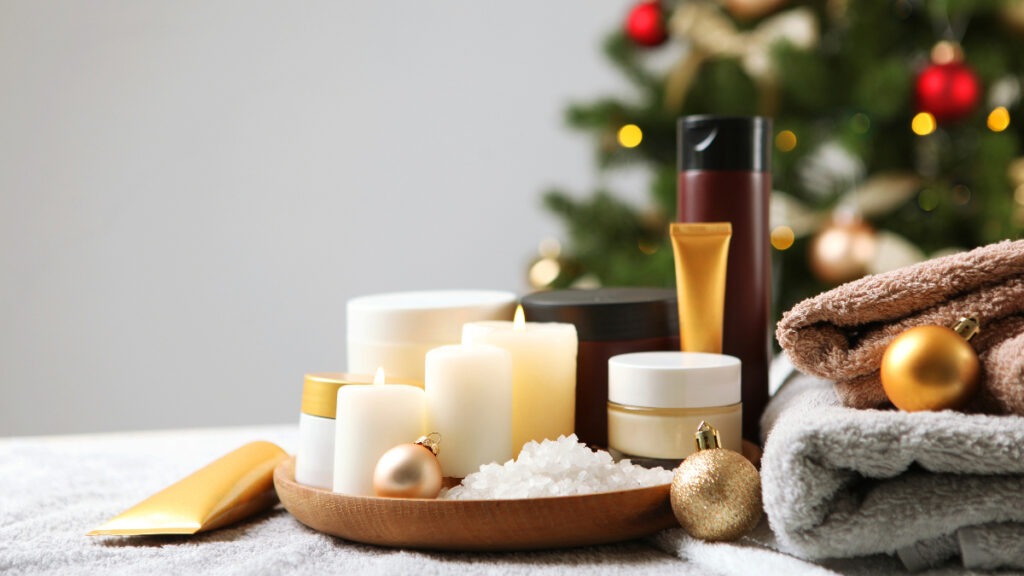 A relaxing spa-themed Christmas gift set for mom who loves skincare with white candles, bath salts, and skincare products on a wooden tray.