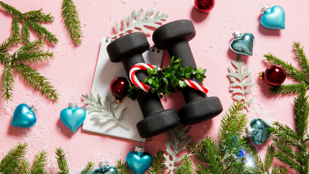 A unique Christmas gift idea for a fitness lover, showing two black dumbbells decorated with a small wreath and candy canes.