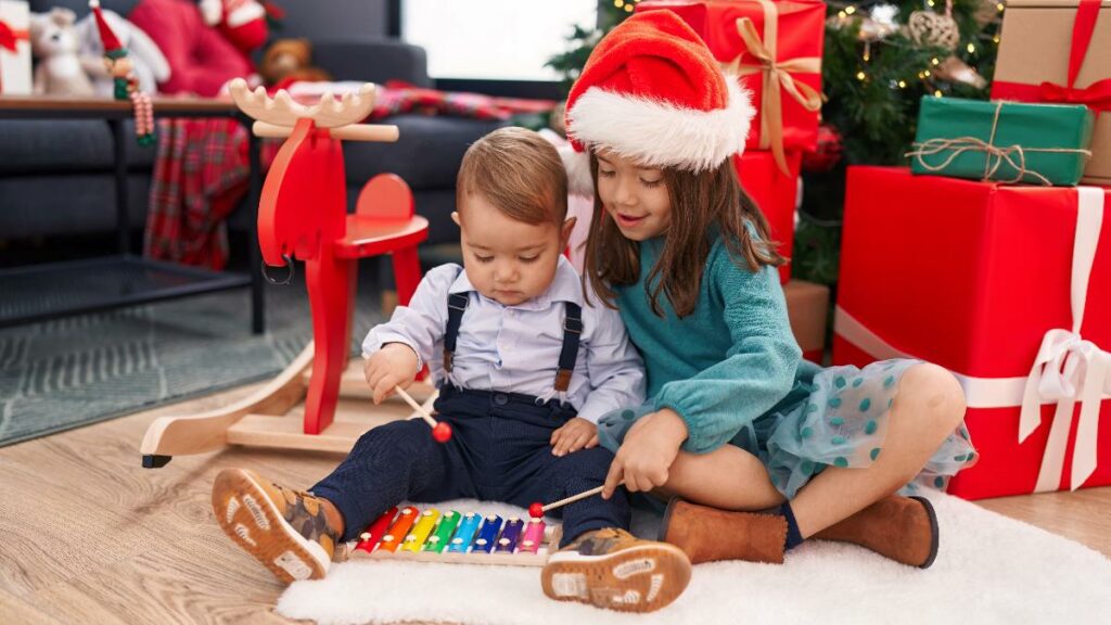 Two young children in Santa hats playing with educational toys on the floor during Christmas time.