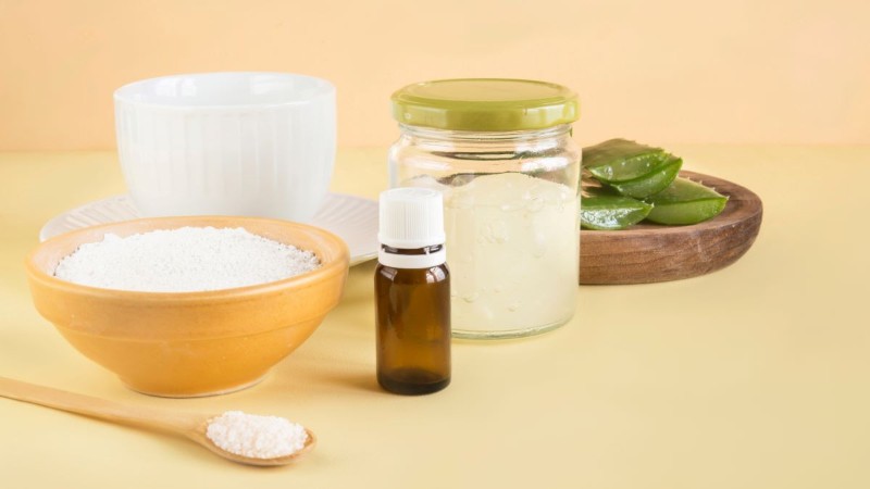 Ingredients for a DIY natural deodorizer, including a jar of baking soda and a bottle of essential oil, used to make carpets and rooms smell amazing.