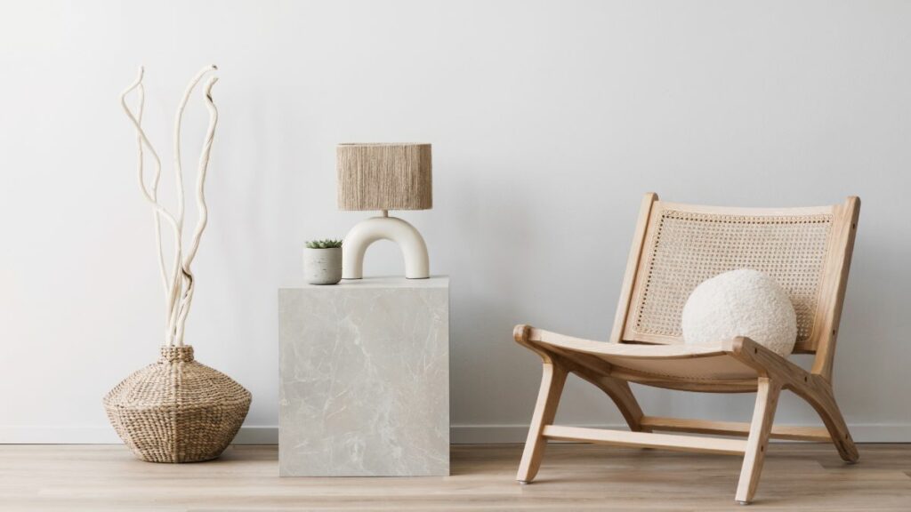 A minimalist interior design corner featuring a modern wooden chair, a unique lamp, and a decorative object on a concrete pedestal.