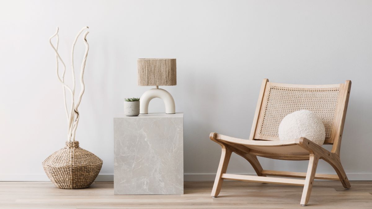 A minimalist interior design corner featuring a modern wooden chair, a unique lamp, and a decorative object on a concrete pedestal.