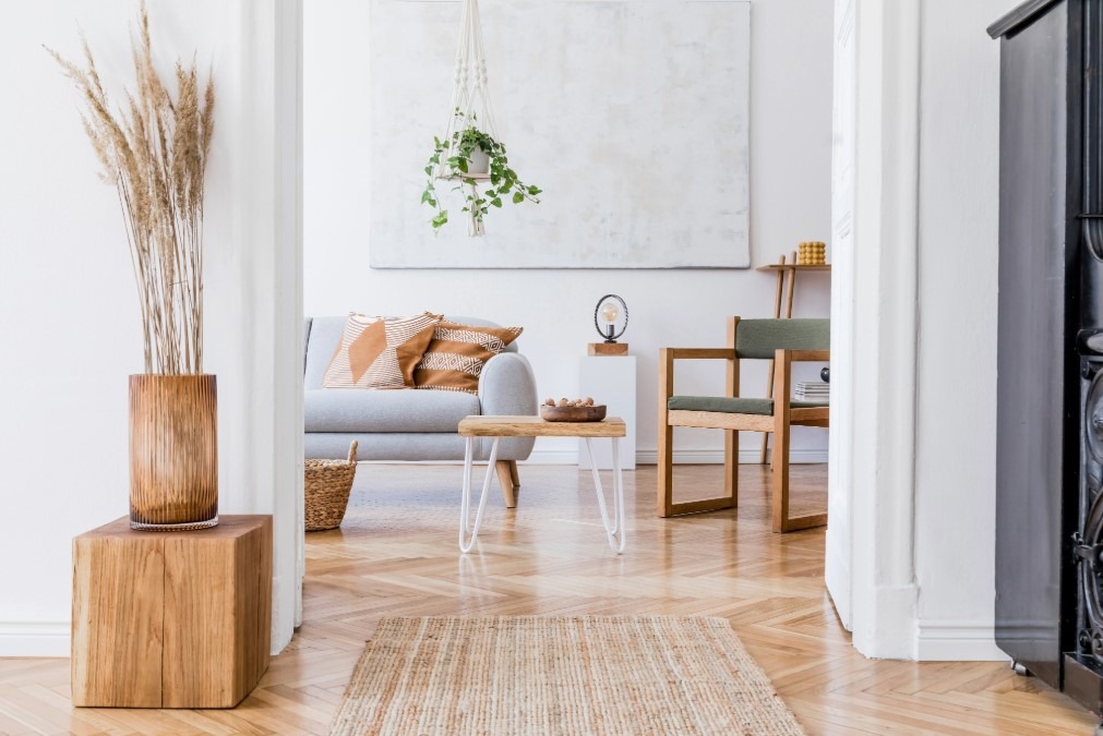 A bright, Scandinavian-style living room with light wood floors and a hanging plant.