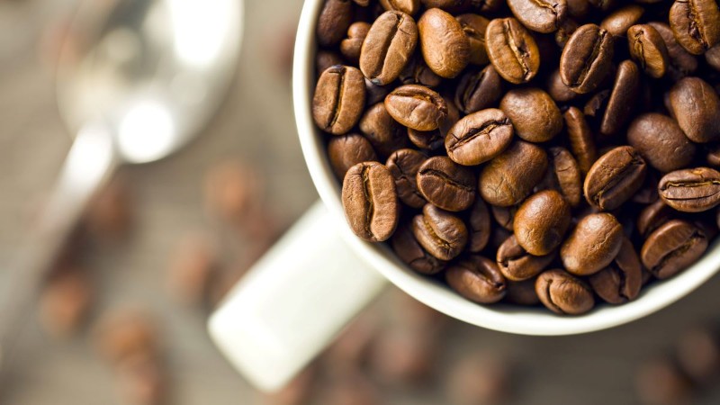 A close-up of fragrant roasted coffee beans in a cup, a natural way to absorb odors or make your kitchen smell amazing.