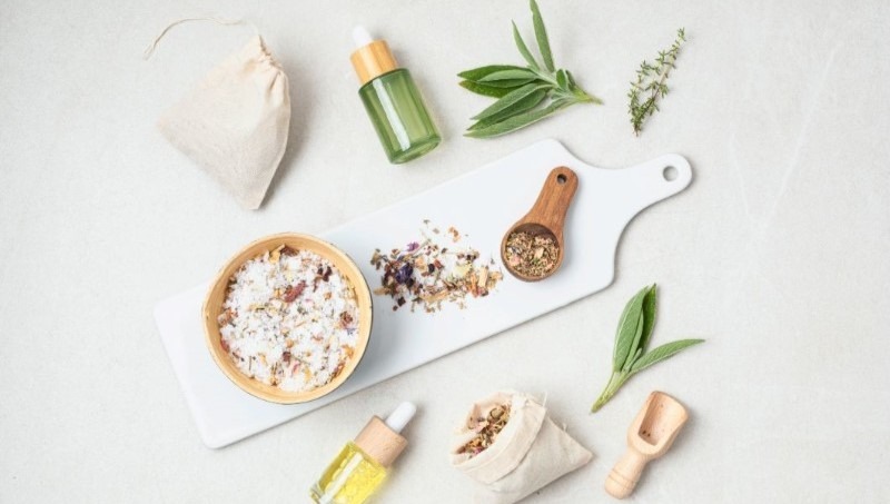 A flat lay of natural ingredients to make your home smell amazing, including DIY potpourri, herbs like sage, and essential oil dropper bottles.