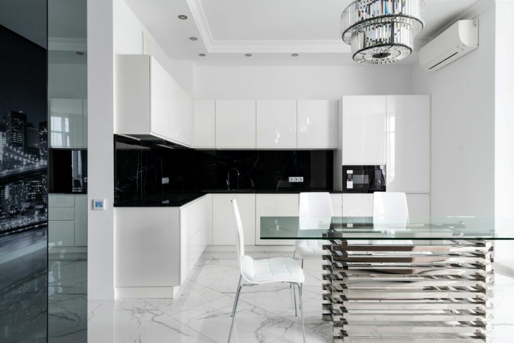 A sleek, modern industrial minimalism in the black and white kitchen and dining area with high-gloss cabinets and chrome chairs.
