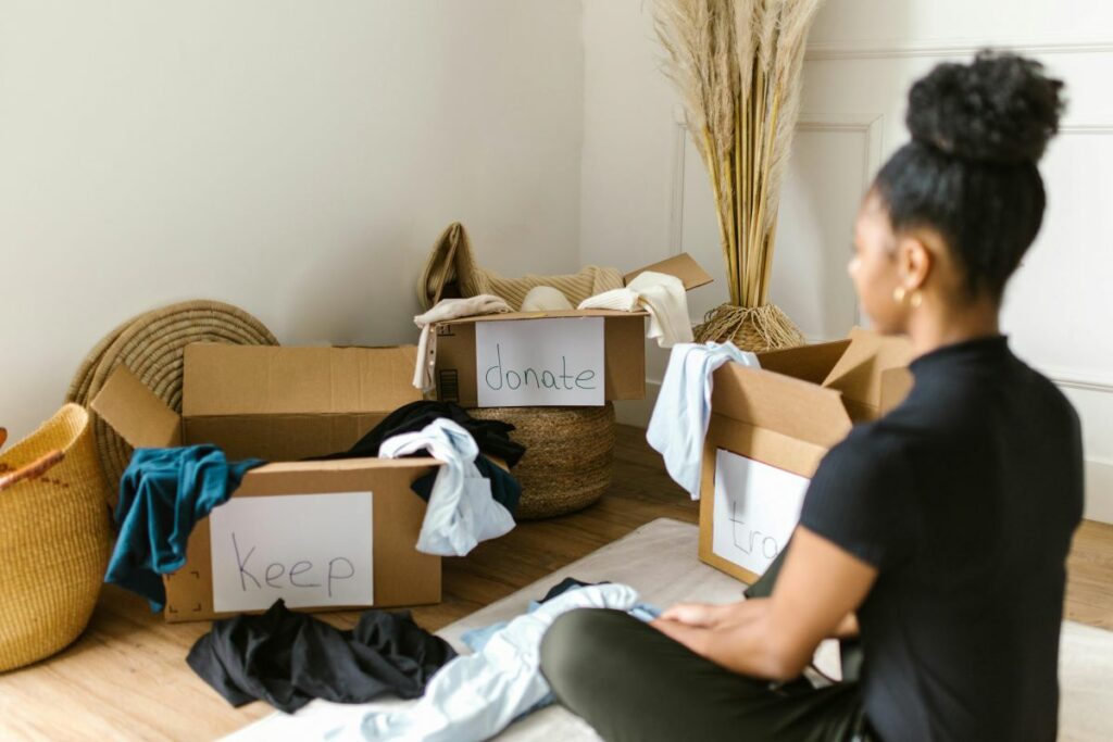 A person sitting on the floor while packing or unpacking cardboard moving boxes.