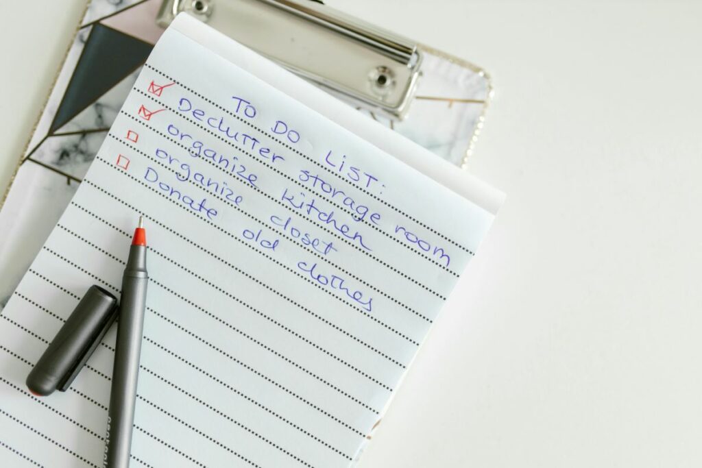 A close-up of a handwritten to-do list on a notepad, with tasks like 'declutter' and 'organize'.