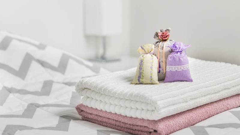 A scented lavender sachet resting on a stack of clean, folded towels, a simple way to make linens and closets smell amazing.