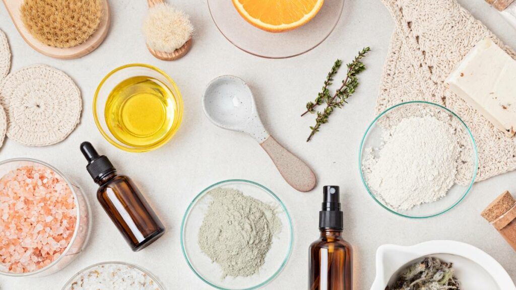 A flat lay of natural skincare ingredients, including clay powder, essential oils, and citrus slices.