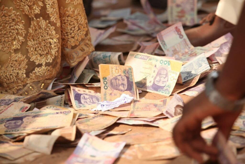 A pile of cash on the floor, illustrating the festive Nigerian wedding tradition of 'money spraying,' where guests shower the couple with money as a gift.