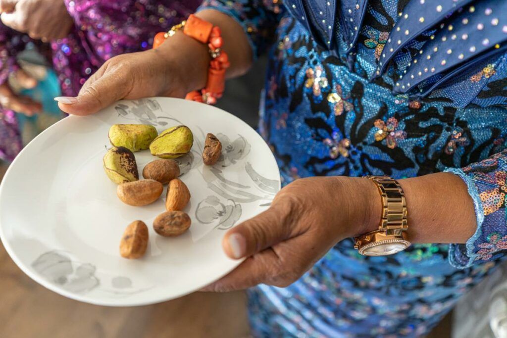A hand holding a plate of kola nuts, an important part of traditional wedding ceremonies in West African cultures, symbolizing hospitality and agreement.