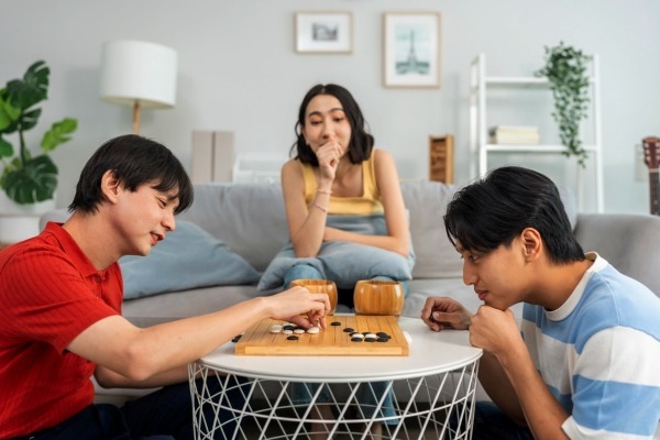 Three friends playing the traditional Asian board game Go, a classic strategy game often enjoyed at social gatherings in countries like China, Japan, and Korea.
