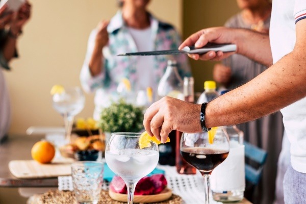Party guests making drinks at a social gathering, representing a creative summer cocktail party theme.