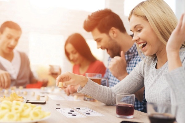 A group of friends laughing while playing a card game, representing a universal party tradition enjoyed with different rules and variations in many countries.