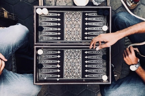 An overhead view of a Backgammon game on an ornate board, representing a popular party game tradition from the Middle East and Greece.