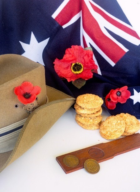 A setup for the traditional Australian gambling game 'Two-up,' played on Anzac Day, featuring coins, an Australian flag, and commemorative poppies.