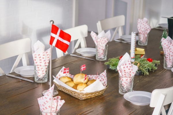 A Danish birthday breakfast table setting, featuring a basket of birthday buns decorated with the Danish flag, a common and cheerful tradition in Denmark.