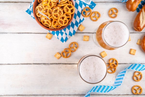 "A German birthday celebration scene featuring a large glass of beer and a bowl of pretzels on a Bavarian-style blue and white checkered napkin.