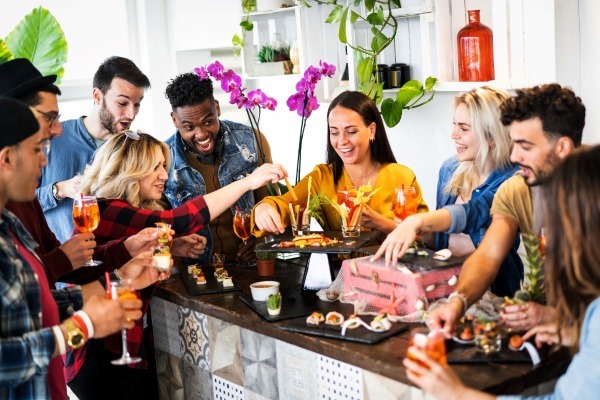 A group of friends laughing together while enjoying an interactive finger food snacks in the kitchen, a creative and social food-themed gathering.