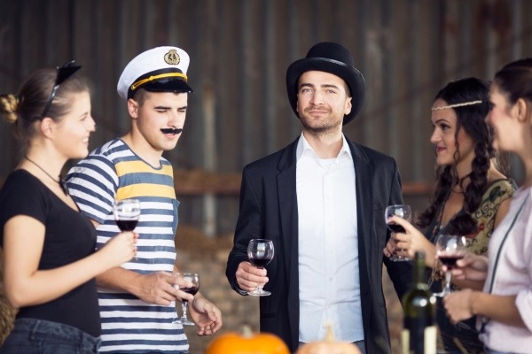 Guests mingling at a costume party, with one man dressed as a sailor and another in a top hat, showcasing a fun and simple dress-up theme.