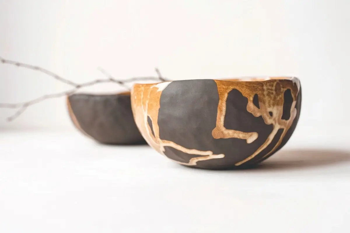 A beautiful example of Kintsugi, a Japanese ceramic bowl that has been repaired with gold lacquer, highlighting its cracks as part of its unique history.