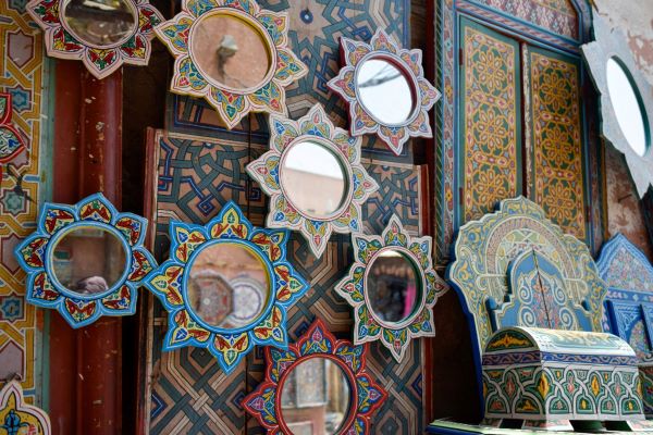 An ornate Moroccan mirrors with an arched top, hanging on a textured colorful wall.