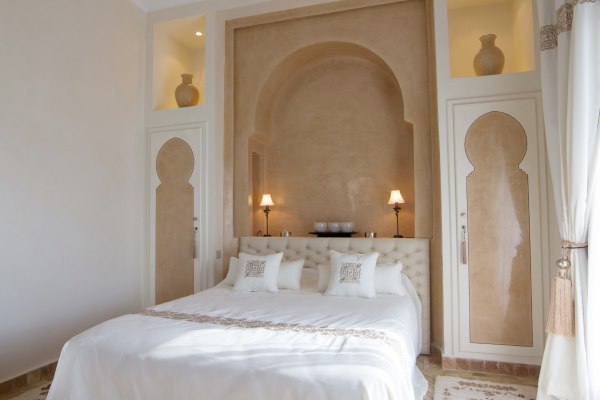 A Moroccan-style bedroom with a white bed, and walls covered with Tadelakt plaster.
